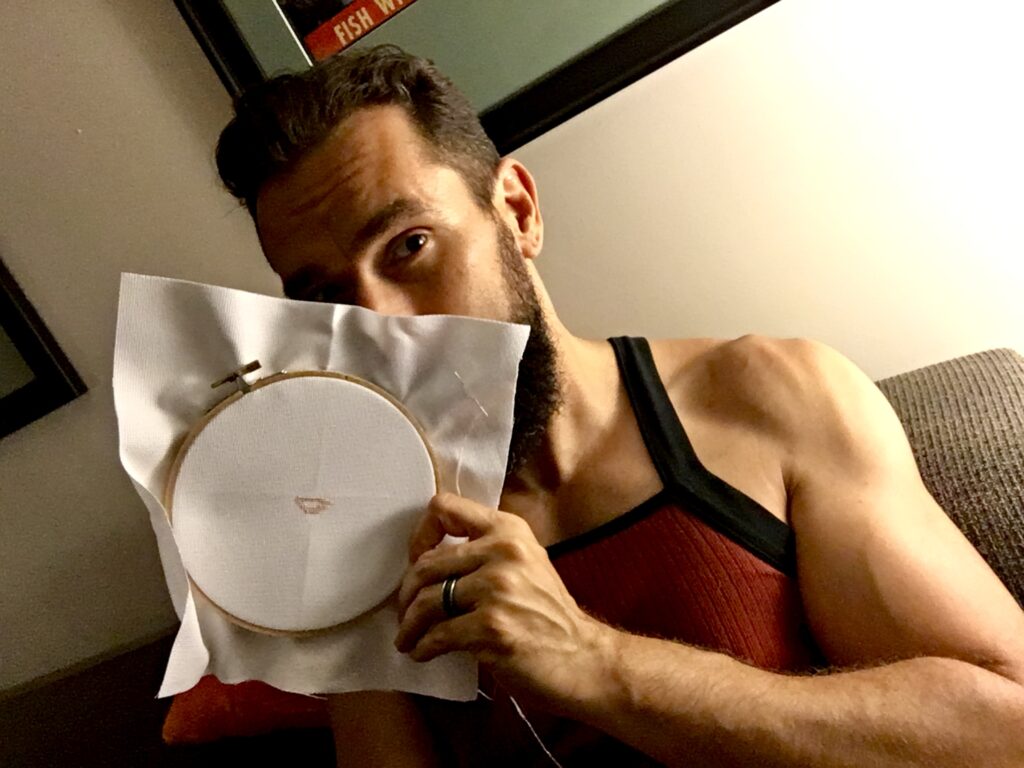 Man holding embroidery ring, starting cross stitch project